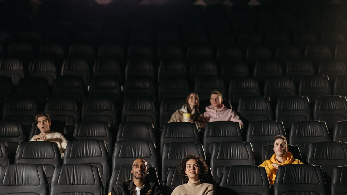 A small diverse group of people watching a movie in an almost empty theater.
